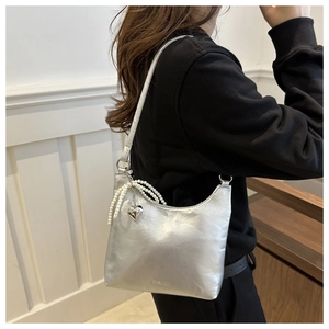 Détail du sac bandoulière argenté métallisé avec pendentif cœur perlé et logo