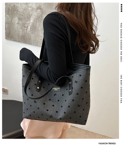 Detail of grey star print tote bag with black handles and leather logo patch