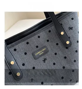 Detail of grey herringbone tote with black polka dots and leather brand logo