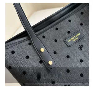Detail of grey herringbone canvas tote with black polka dots and leather handle rivets