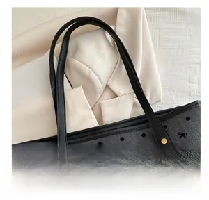 Detail of chevron tote bag with black polka dots, gold rivets and leather handles