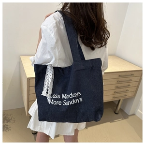 Vue détaillée du sac cabas en jean avec texte imprimé blanc et ruban en dentelle chic