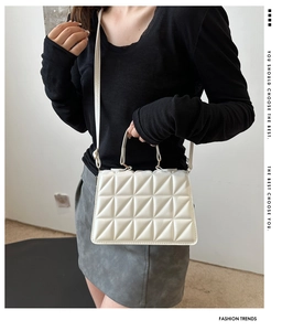 Detail of white quilted crossbody bag featuring a unique geometric triangular stitch pattern