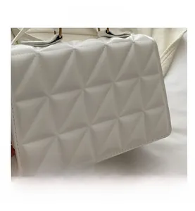 Close-up of white PU shoulder bag with geometric triangle quilting and metal hardware
