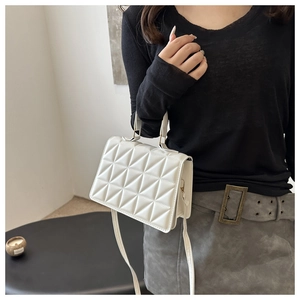 White geometric quilted handbag with shoulder strap worn by a model in casual outfit