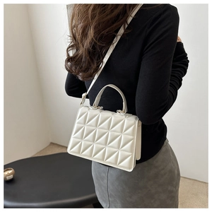 Detail showing the geometric quilted texture and gold-tone clasp of a white crossbody bag