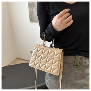Detail of beige quilted leather handbag featuring a crossbody strap on model