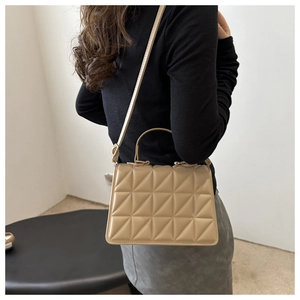 Detailed side view of beige quilted shoulder bag with fine texture and adjustable strap
