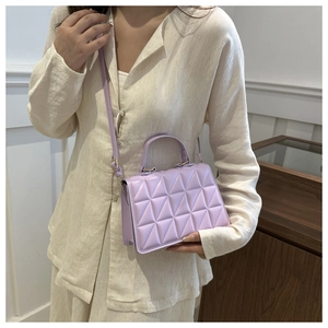 Detail of light purple quilted handbag with adjustable strap in a stylish lifestyle setting