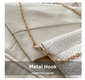 Detail shot of the white woven texture and premium gold metal chain on a bucket bag
