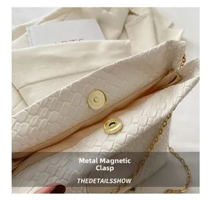 Detail of white woven textured bucket bag with gold magnetic snap closure and chain
