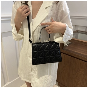 Detail of black quilted PU leather handbag with gold hardware and long shoulder strap