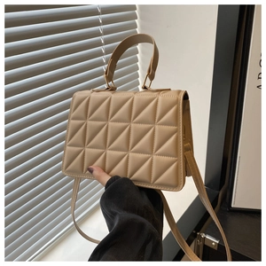 Detail of beige quilted handbag with gold hardware and triangular stitching patterns