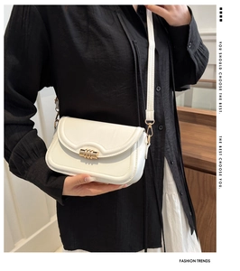 Detail of white leather crossbody bag featuring a golden triple-ring rotary metal clasp