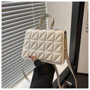 Detailed view of white quilted crossbody bag with gold hardware and top handle