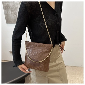 Brown woven texture crossbody bucket bag with gold chain strap shown on model