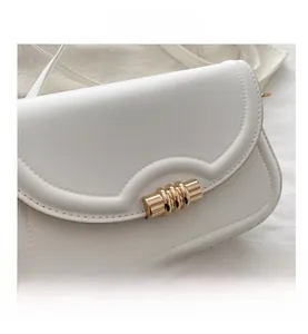 Close-up of white leather square bag with wave flap and golden cylindrical metal clasp