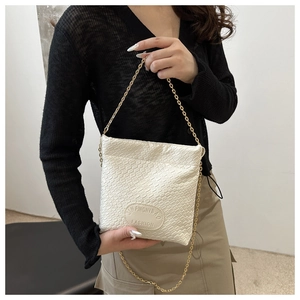 Detail of white woven texture shoulder bag with gold chain strap and embossed logo