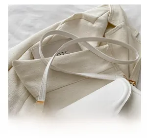 Detail of white faux leather crossbody bag with adjustable strap and golden metal clasp