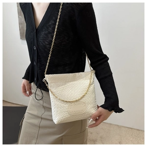 Cream woven texture chain bucket bag worn by model with minimalist spring outfit