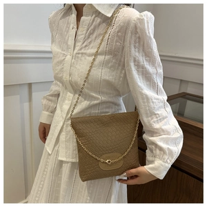 Close-up of brown woven bucket bag featuring golden chain strap and leather patch