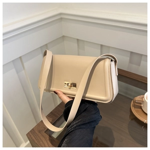 Detail of elegant beige square shoulder bag featuring a gold rectangular twist lock