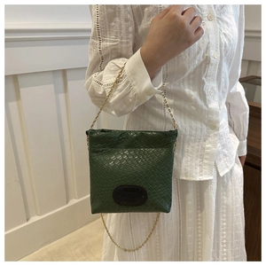 Detail of dark green woven leather crossbody bag with golden chain strap and logo patch
