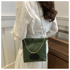 Detail of dark green woven texture shoulder bag with gold chain strap on model