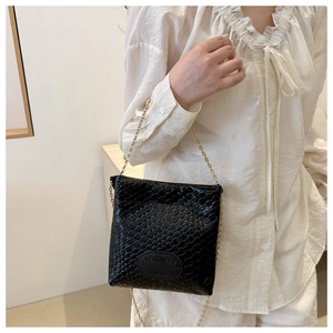 Close-up of black woven texture shoulder bag with elegant gold chain strap on model