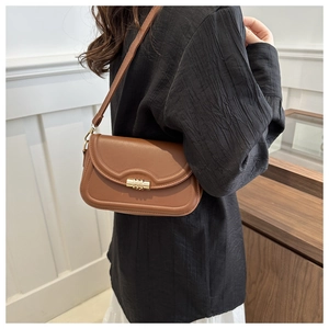 Detailed side view of caramel leather crossbody bag with golden cylinder lock and slim strap