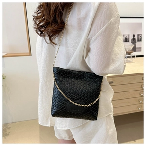 Detail of black woven leather crossbody bag with elegant gold chain strap and metal logo