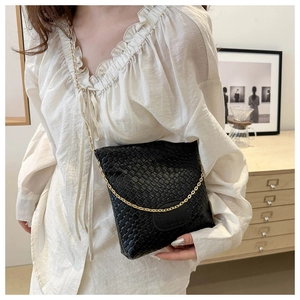 Detail of black woven leather bucket bag with gold chain strap and Fashion patch