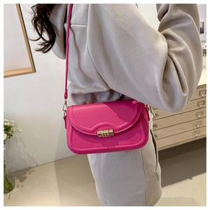 Close-up of rose red PU leather crossbody bag with wave flap and gold turn-lock closure