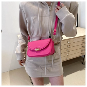 Crossbody bag in rose pink with gold cylinder lock shown as model lifestyle detail