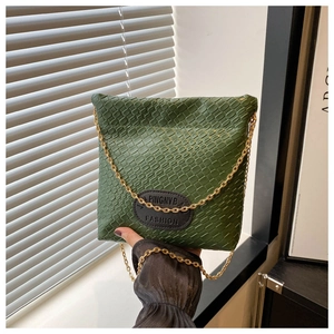 Green woven texture bucket bag with gold chain strap shown in a stylish interior