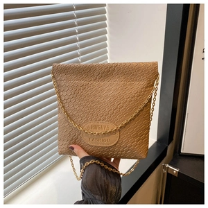 Close-up of khaki woven texture and embossed leather logo on a stylish crossbody bucket bag