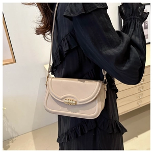 Detail of beige faux leather square bag with gold cylindrical twist lock and stitching