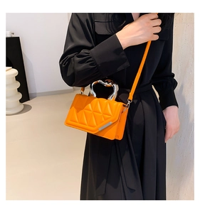 Model wearing a bright orange quilted leather handbag with a unique silver metal handle