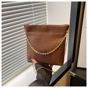 Detailed close-up of brown woven texture leather bucket bag with gold chain strap