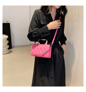 Detail of pink quilted handbag featuring metallic heart handle and silver trim accents