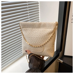 Close-up of beige woven texture and gold chain strap on a stylish bucket bag
