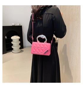 Detail of fuchsia quilted handbag with triangular stitching and silver U-shaped metal handle