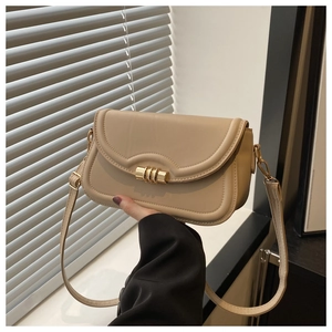 Close-up of a cream crossbody bag featuring a golden triple-ring lock and leather strap