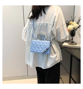 Close-up of light blue quilted shoulder bag with unique silver metallic handle details