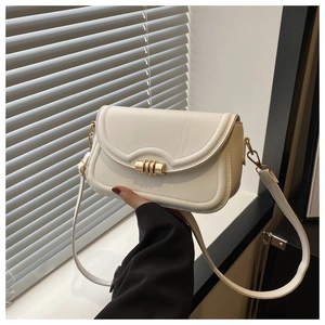 Close-up of cream square bag with cylindrical gold metallic twist lock and sleek stitching
