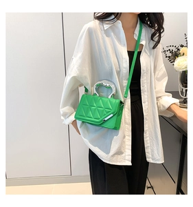 Bright green quilted crossbody bag featuring a unique silver metallic handle worn by model