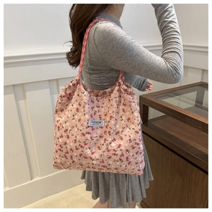 Detail of floral nylon tote bag featuring pink braided straps and fashion label