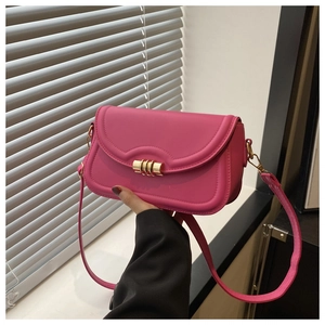 Detail view of pink crossbody bag with scalloped flap and gold cylindrical metal clasp