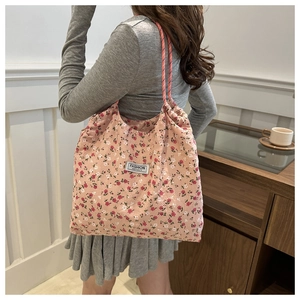 Detail of pink floral nylon tote bag with drawstring shoulder strap and fashion label