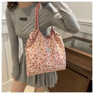 Close-up of pink floral drawstring tote with braided rope handle and fashion label